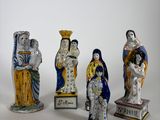 cinq figurines de tailles et de couleurs différentes posées sur une surface blanche