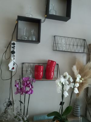 two vases with flowers on a table in front of a wall