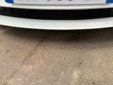 the front end of a white car with a blue stripe on it