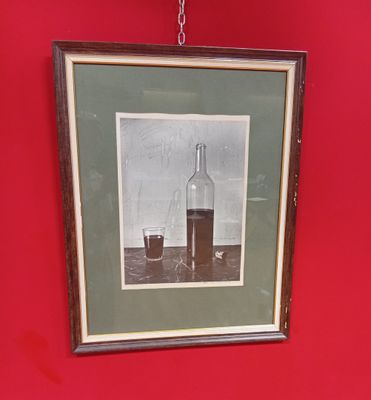 une photo représentant une bouteille et un verre accrochés à un mur rouge