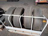 four tires stacked on top of a cart in a parking lot