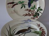 deux assiettes avec des oiseaux peints dessus, posées sur une table