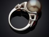an image of a white pearl and diamond ring on a black surface