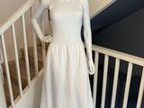 mannequin vêtu d'une robe blanche et d'un chapeau de paille, debout sur un escalier