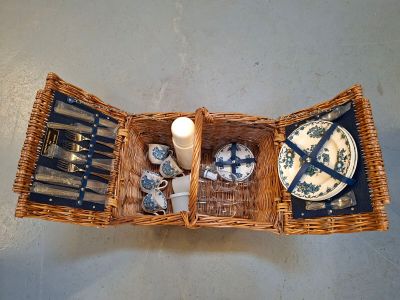 un panier de pique-nique en osier contenant des assiettes et des couverts