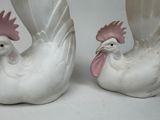 pair of white ceramic roosters with pink beaks on a white background