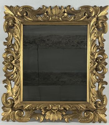 a gold framed mirror on a wall next to a white wall