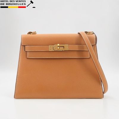 un sac à main en cuir marron muni d'un fermoir en métal doré sur la poignée