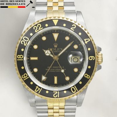a rolex watch with a black dial and gold bezel