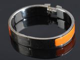an orange and black bracelet sitting on top of a black surface