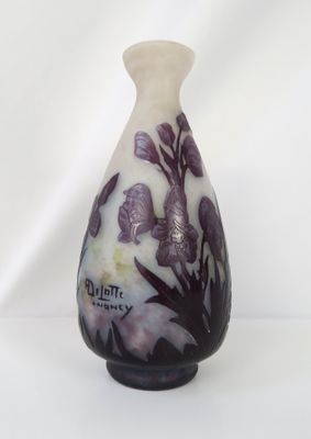un vase blanc orné de fleurs violettes, posé sur une table