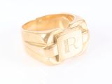 une photo d'une bague en or sur laquelle figure la lettre « r »