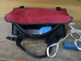 un sac rouge et noir posé par terre à côté d'une paire de ciseaux et d'une paire de ciseaux