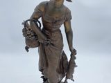 statue of a woman holding a basket of flowers on a white surface
