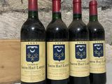 trois bouteilles de vin rouge posées sur un comptoir, à côté d'une caisse en bois