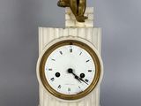une petite statue représentant un garçon assis sur le cadran d'une horloge
