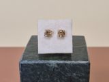 a pair of gold stud earrings sitting on top of a marble block