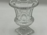 a glass vase on a stand on a white surface