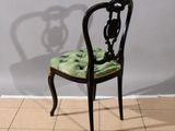an image of a black chair with a green seat and a shadow of a vase on the wall