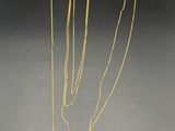 un collier en or composé d'une longue chaîne et orné d'une fleur