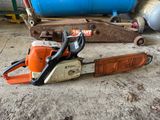 a chainsaw sitting on the ground next to a blue container