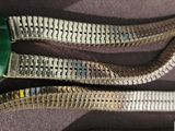 a close up of a metal belt with a green button on it