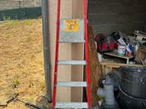 a ladder that is leaning against a wall next to a pile of junk