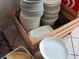 many plates and bowls in a wooden box on the floor