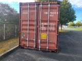 a red shipping container sitting on the side of the road