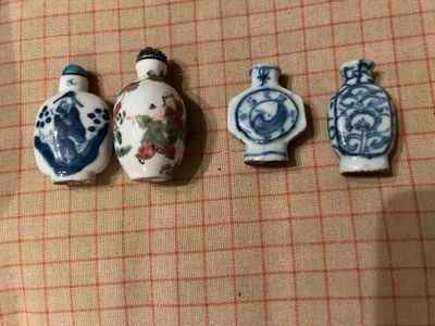 Trois petits vases chinois sont alignés sur une nappe à carreaux.