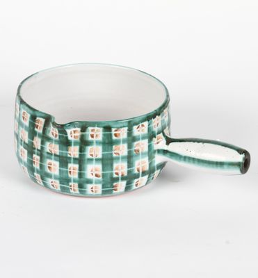 une tasse verte et blanche avec une anse, posée sur une surface blanche