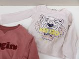 two sweatshirts that are sitting on a white table