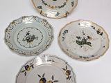 four plates with floral designs are arranged on a white surface