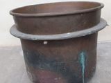 a large metal pot sitting on the floor in front of a white wall