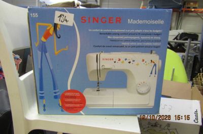 une boîte contenant une machine à coudre, posée sur une chaise