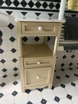 une petite armoire dans un coin de la salle de bains