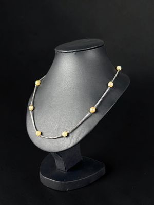 a black mannequin with a gold beaded necklace on it