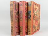 trois vieux livres sont empilés sur une surface blanche