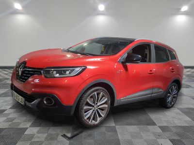 une voiture rouge est garée dans une pièce au sol en damier