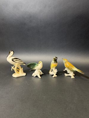 three small figurines of birds and a bird on a table
