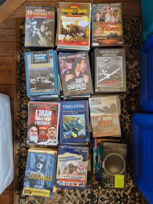 beaucoup de DVD par terre, à côté d'un fauteuil bleu