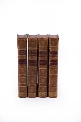quatre vieux livres posés l'un sur l'autre sur une surface blanche