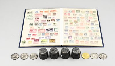 un livre ouvert, sur lequel sont posés des timbres et des pièces de monnaie, posé sur une table