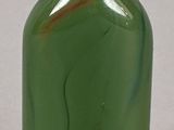 a green glass bottle with a white cap sitting on a table