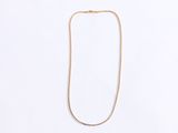 a gold necklace with a long chain on a white background