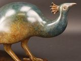 un gros plan sur une statue de paon posée sur un socle en bois