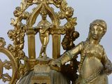 a gold clock with a statue on top of it