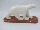 a white polar bear statue on a red marble base