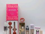 le contenu d'une boîte de maquillage rose est présenté sur une surface blanche