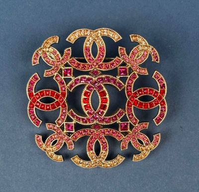 a close up of a brooch with red and yellow stones